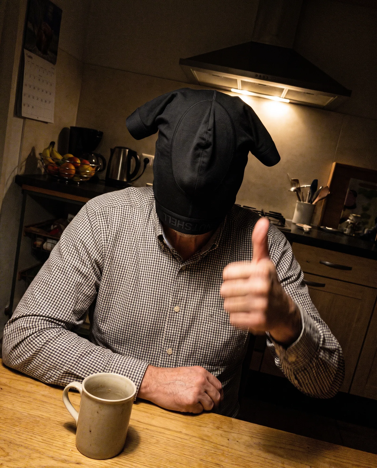 Man aan de keukentafel met de boxershort over zijn hoofd, alleen zijn neus steekt eruit