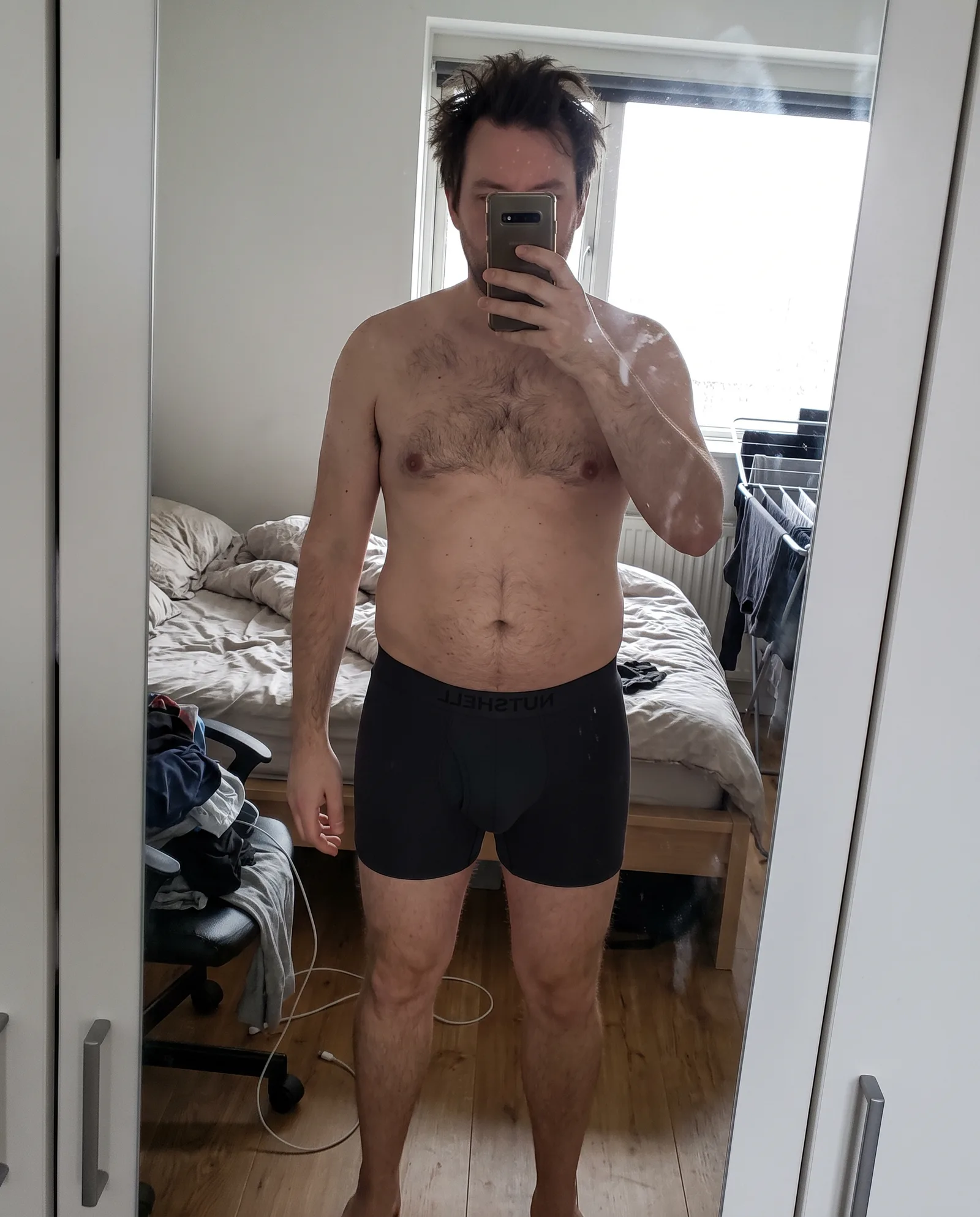 Man maakt 's ochtends een spiegelselfie in de slaapkamer